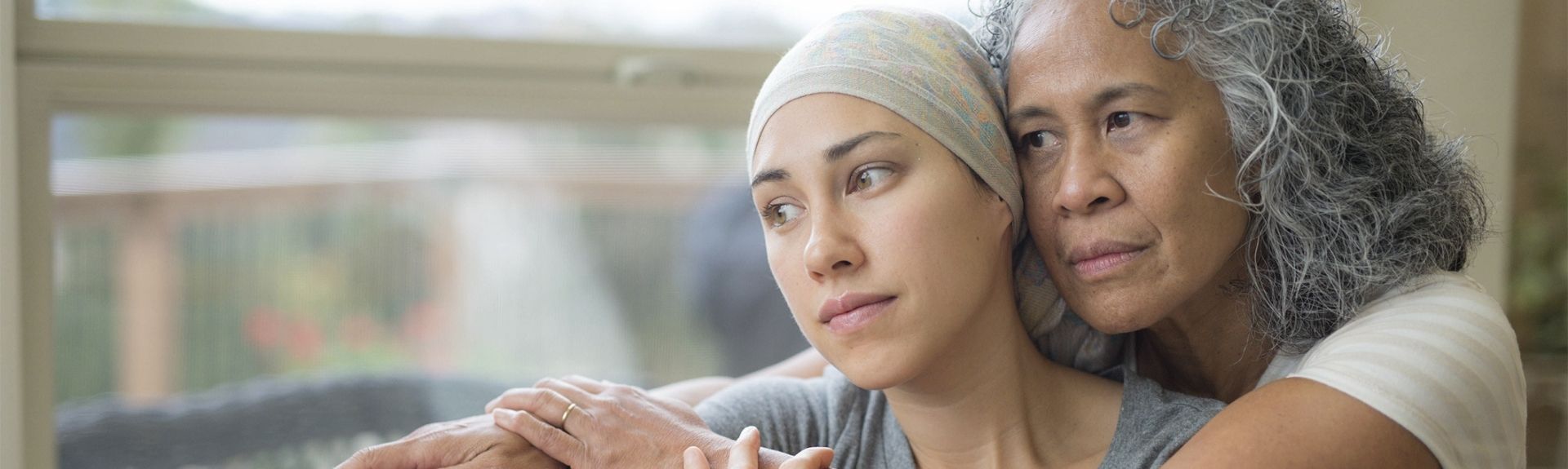 women cuddling daughter going through cancer treatment