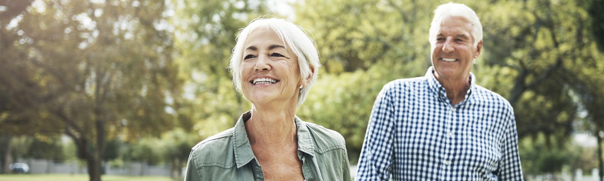 Mature Aged couple walking in park smiling