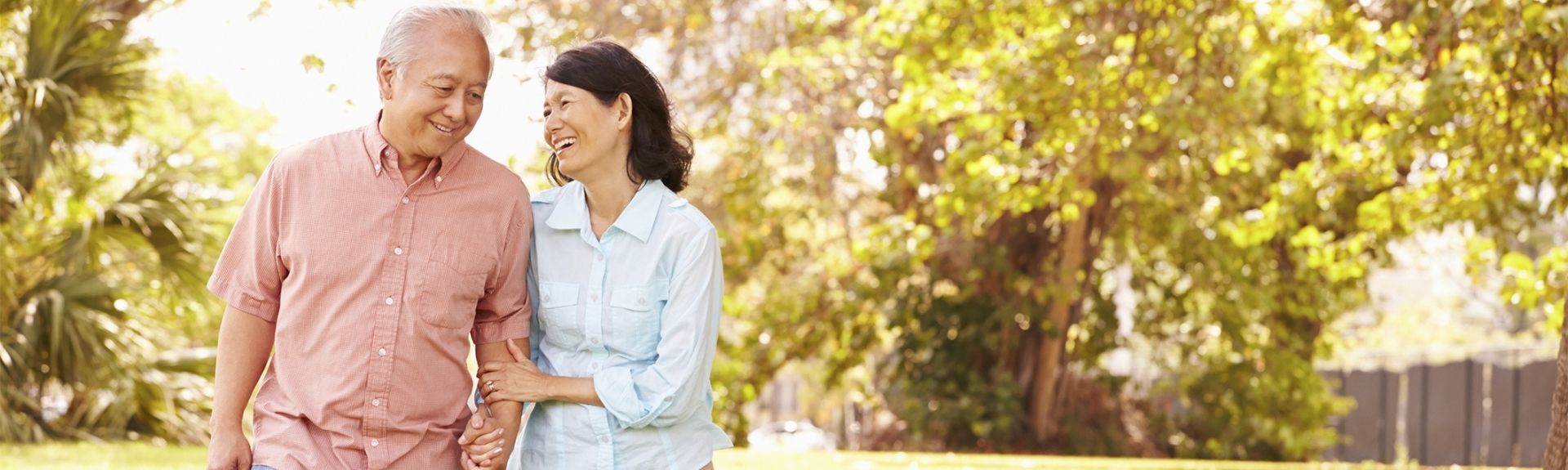 Asian couple holding hands walking in park